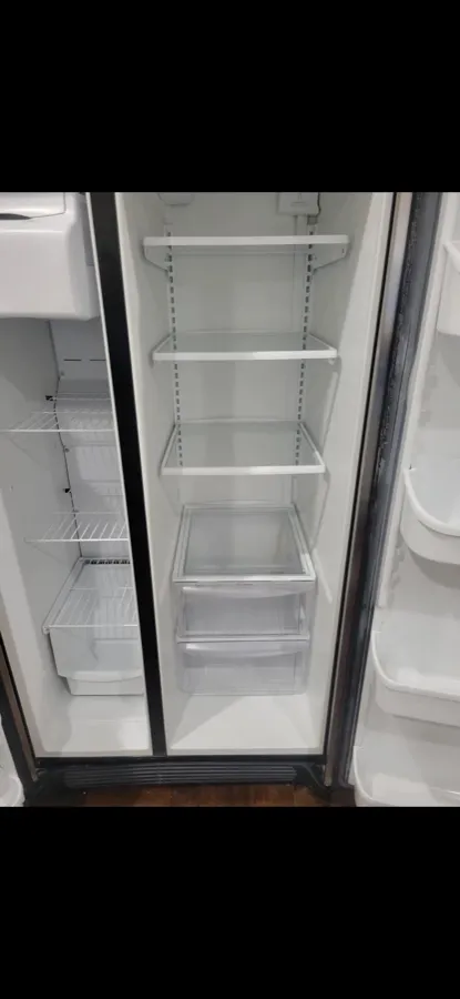 The inside of a refrigerator cleaned by Happy Maids, shelves and bins empty and wiped
