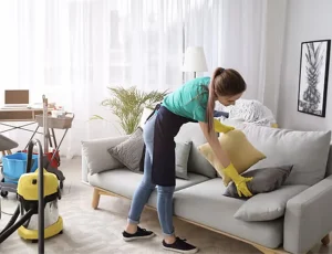 Person cleaning and arranging cushions.